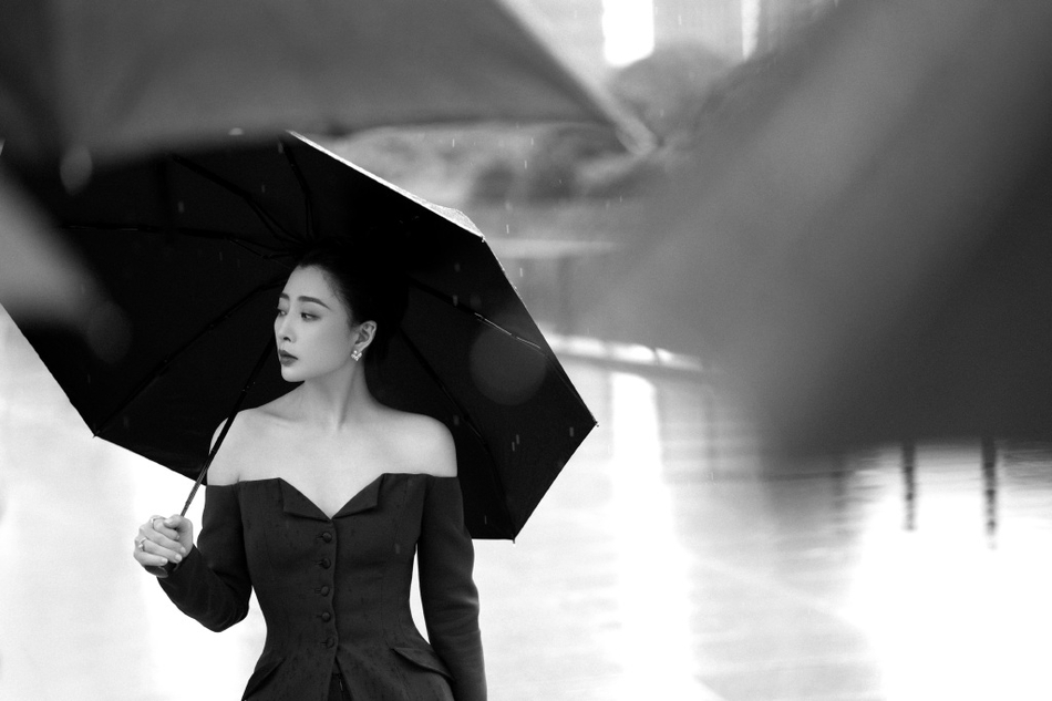 殷桃雨中撑伞漫步街头 穿露肩西装潇洒利落