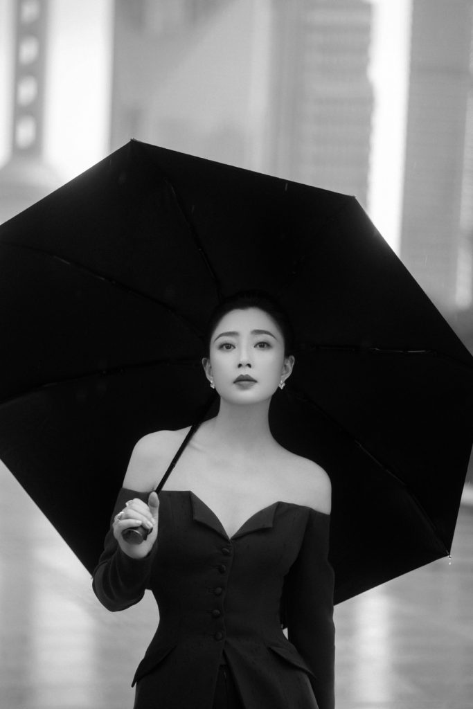 殷桃雨中撑伞漫步街头 穿露肩西装潇洒利落