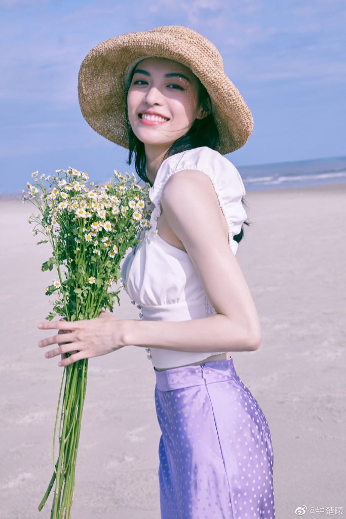 钟楚曦穿紫裙捧雏菊海边奔跑 回眸对镜甜笑