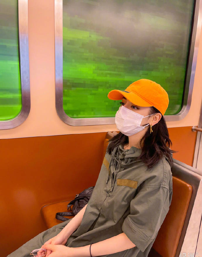 热巴晒出行穿搭 橘帽配墨绿外套活力满满